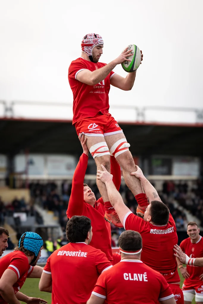 Joueur du Stade Langonnais s’élevant pour récupérer le ballon avec l’aide de ses coéquipiers lors d’un entraînement avant match